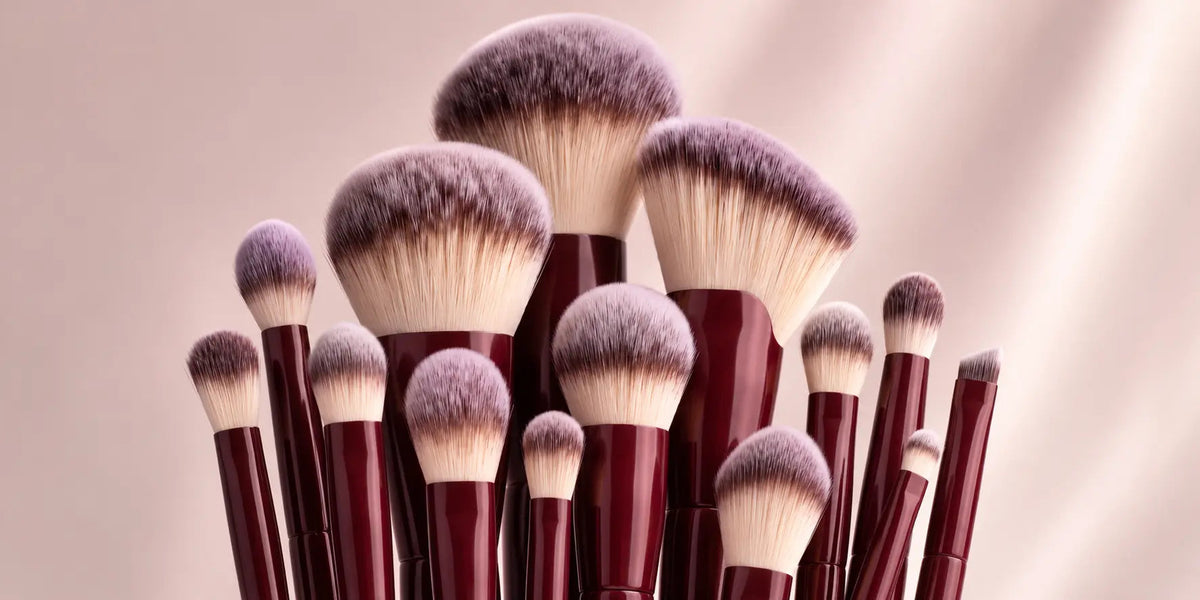 Wijnrode make-up kwasten tegen een roze achtergrond, sfeerbeeld bij de Flawless keuzehulp