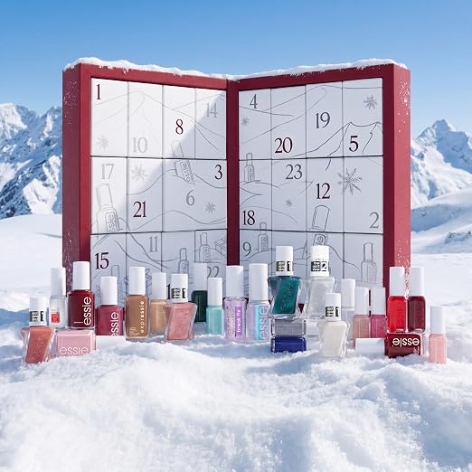 Essie adventskalender in de sneeuw, met besneeuwde bergen erachter en de flesjes ervoor